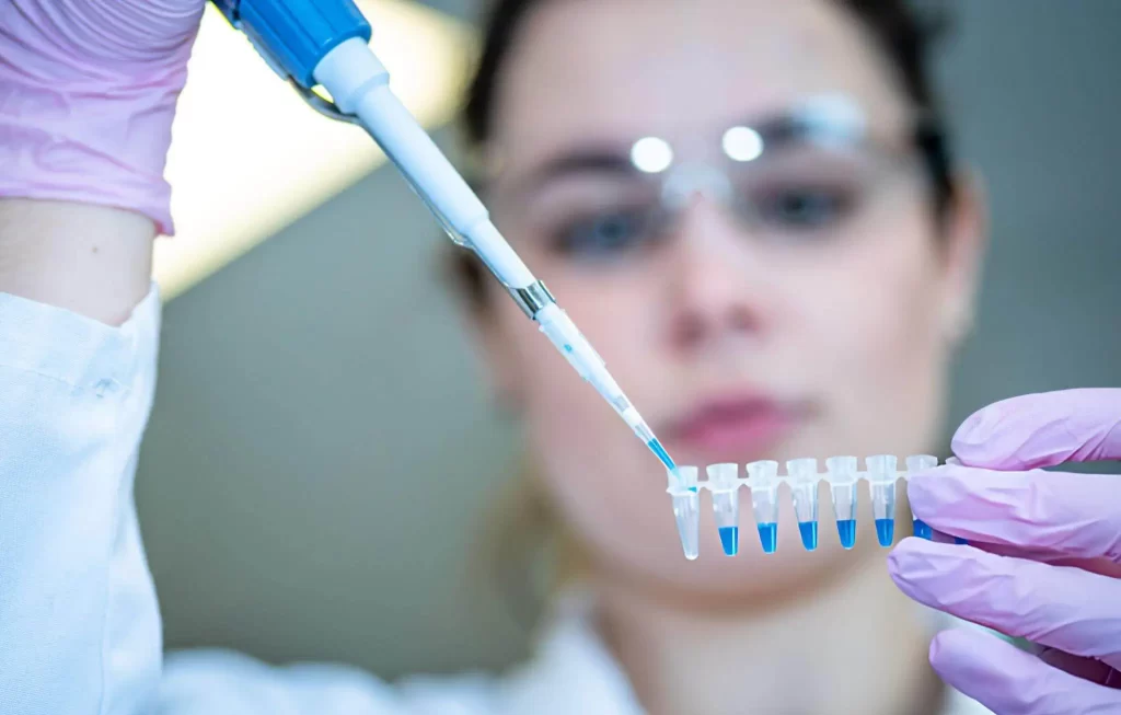 Lab technician using a pipette to analyze regenerative medicine samples in vials